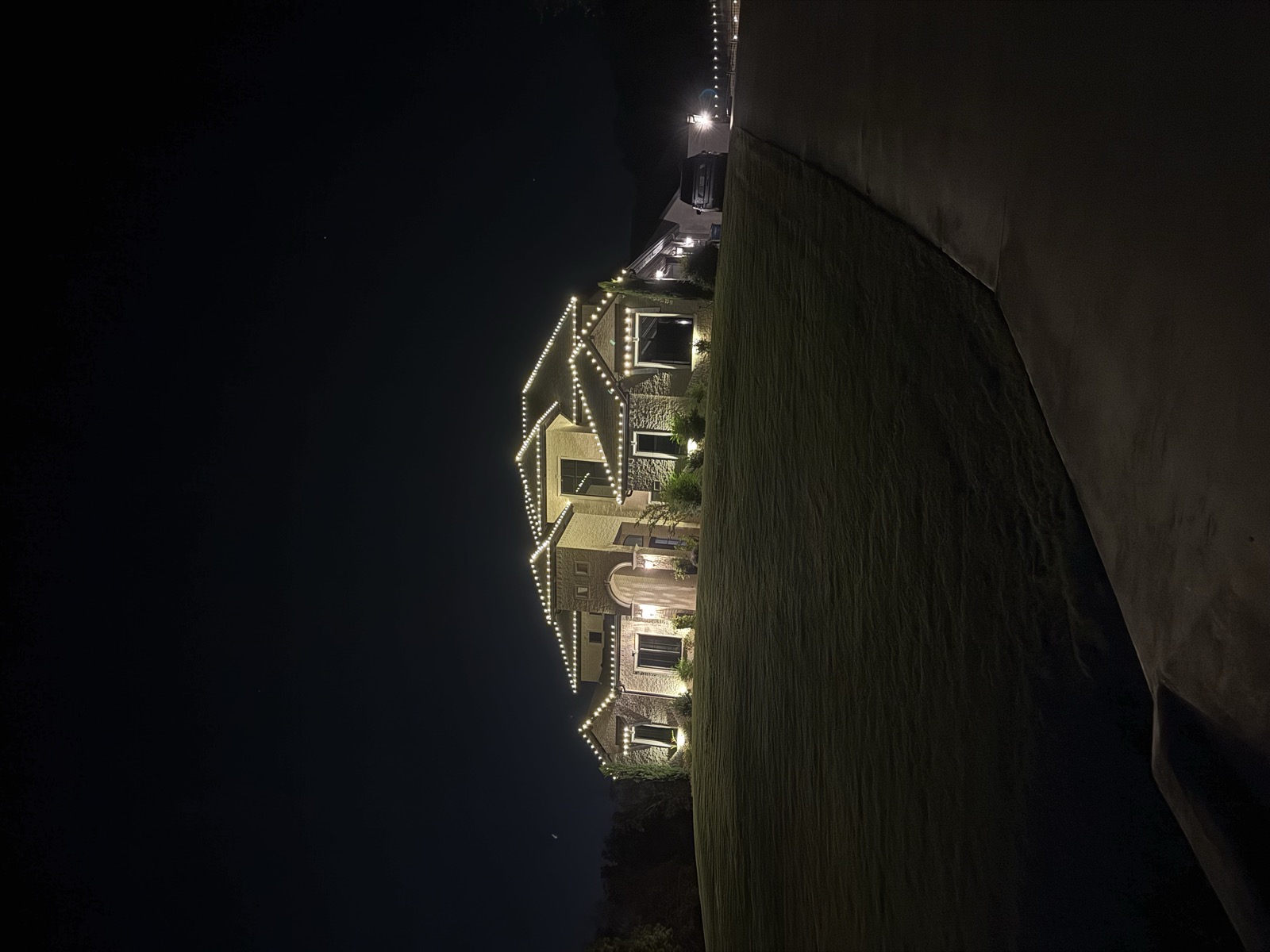 Large stucco home on a hill with warm white roofline lighting